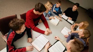 Youth group with a teacher reading the Bible during a church meeting